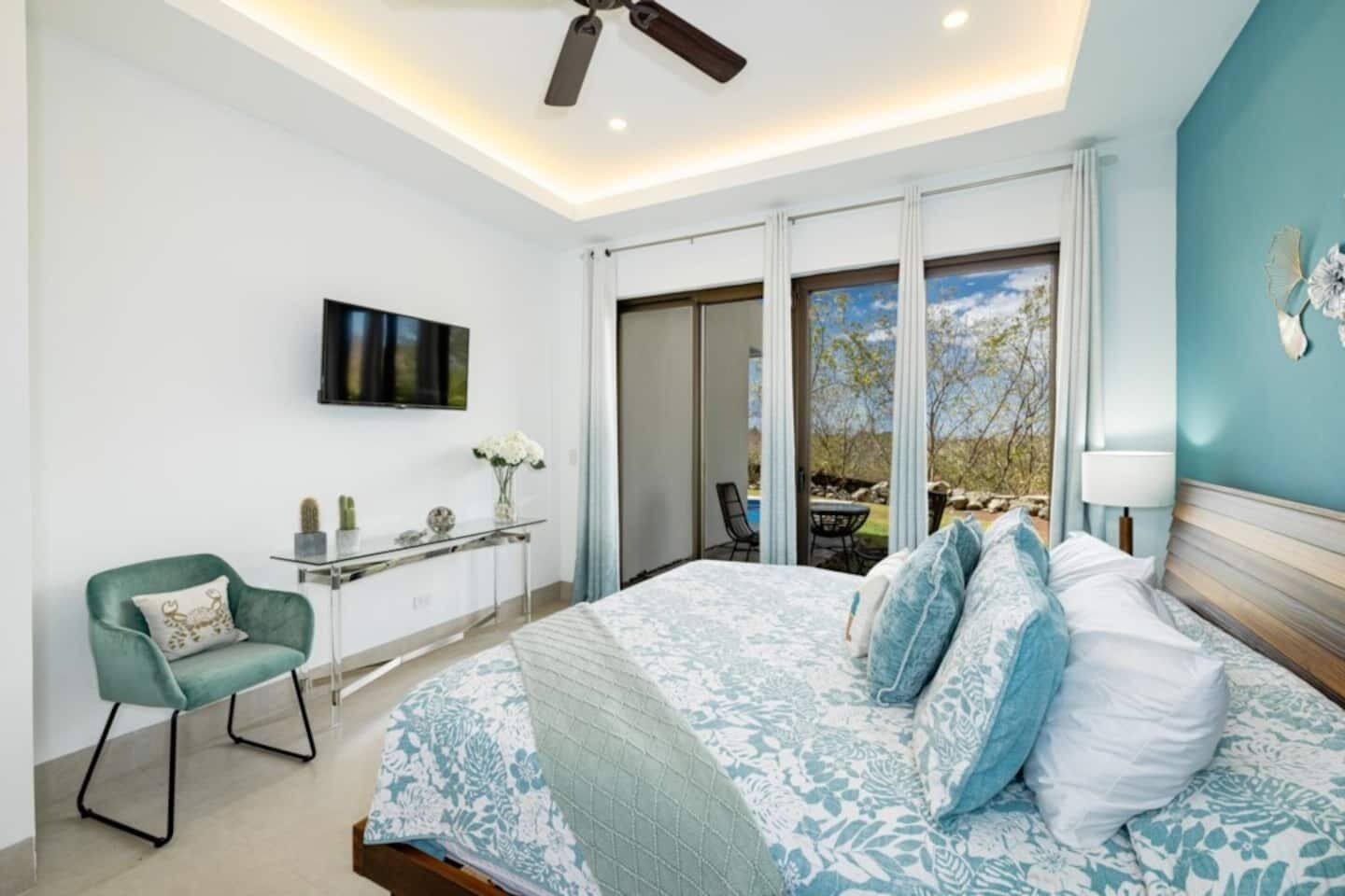 Une chambre avec un grand lit, un bureau, une chaise, un téléviseur et une vue sur l’extérieur.