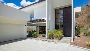 Una moderna casa a due piani con un portico coperto, un garage e un giardino curato.