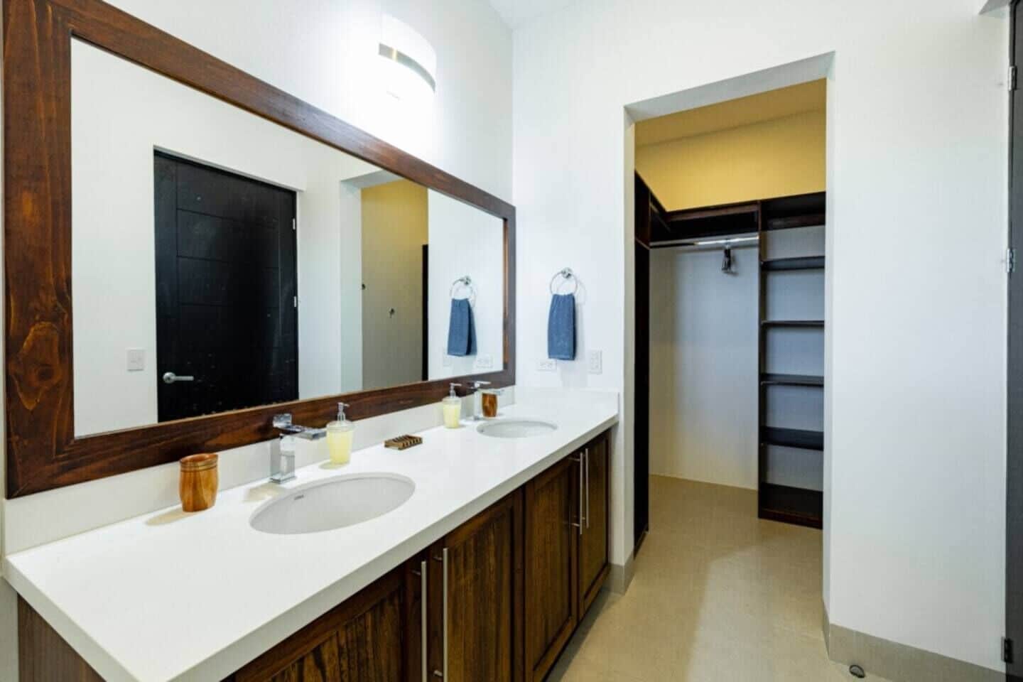 A bathroom with a large mirror, two sinks, wooden cabinets, and a towel rack.