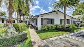 A modern building with a white exterior, surrounded by well-maintained landscaping including palm trees and hedges. - Beautiful spacious 2bd, w/d, bbq, yard, pets allowed, free parking  (Delray Beach)