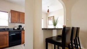 A kitchen with wooden cabinets, a black dishwasher, and a countertop with a toaster. - National Park Home Base Between Miami & The Keys (Homestead)