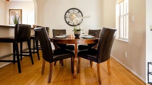 A dining area with a wooden table, black leather chairs, and a decorative wall clock. - National Park Home Base Between Miami & The Keys (Homestead)