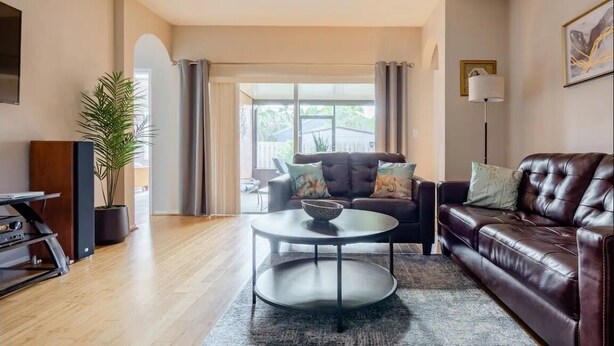 A living room with a brown leather sofa, a round coffee table, and a television on a stand. - National Park Home Base Between Miami & The Keys (Homestead)