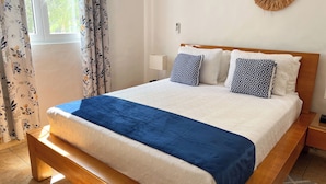 A neatly made bed with a blue blanket, white bedding, and patterned pillows. - Modern 2BR in Cabarete • Pool • Beach Walk (Cabarete)