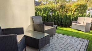 An outdoor patio area with wicker furniture, including a table and chairs, and a lamp post. - Apartment Famli Relax **** Villa Störtebeker in Göhren (Göhren)