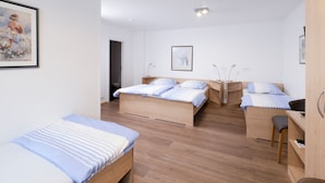 Une chambre d’hôtel avec deux lits, un bureau et une chaise. Il y a un tableau au mur et une porte qui donne sur la salle de bain.