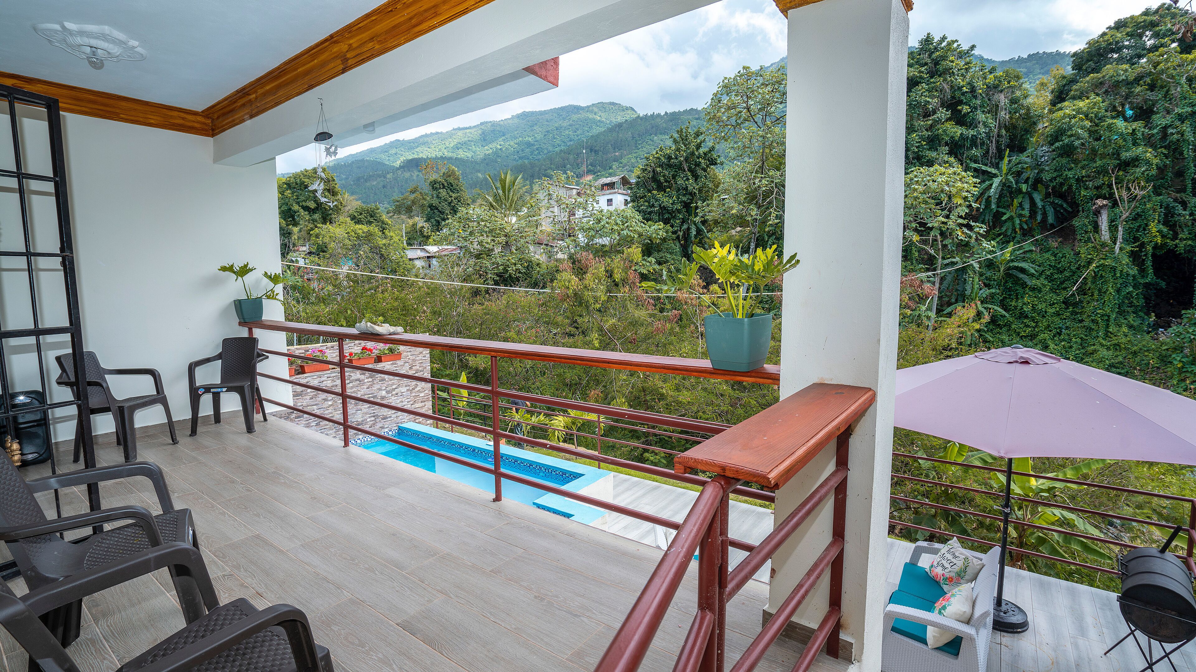 A balcony with a pool, wooden flooring, and a view of a mountainous landscape.