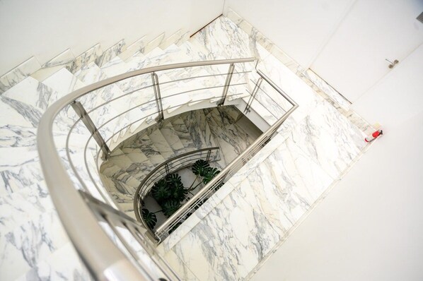 A spiral staircase with marble steps and metal railings, leading to a lower level.
