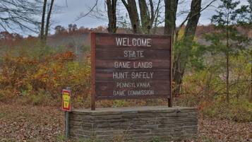 Uma placa de madeira com a inscrição Pennsylvania Game Lands, incluindo um lembrete de segurança.