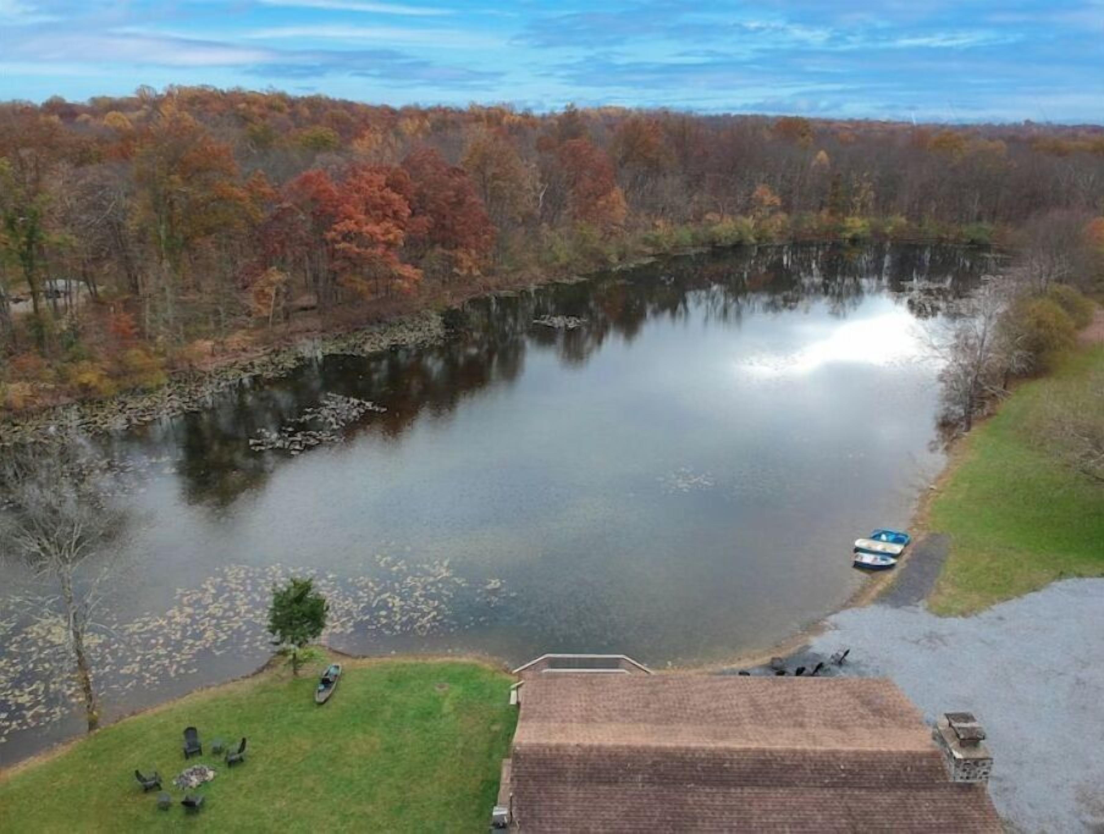 A lakeside property with a dock, a grassy area with chairs, and a building with a sloped roof.