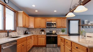 A modern kitchen with wooden cabinets, stainless steel appliances, and a large island. - Kettle Creek Hills Lodge: Exceptional Views! (Elk Township)