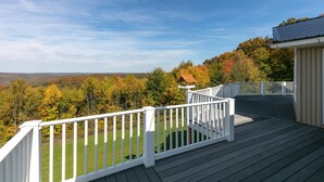 A deck with white railings overlooking a scenic landscape with autumn foliage. - Kettle Creek Hills Lodge: Exceptional Views! (Elk Township)