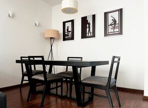 Un coin repas avec une table et des chaises, un lampadaire et des tableaux encadrés au mur.