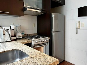 A kitchen with a gas stove, oven, refrigerator, and a microwave.