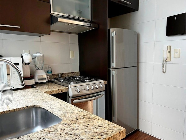 A kitchen with a gas stove, oven, refrigerator, and a microwave.
