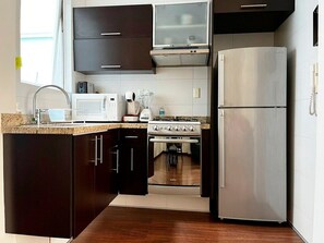 A modern kitchen with dark cabinetry, stainless steel appliances, and a microwave.