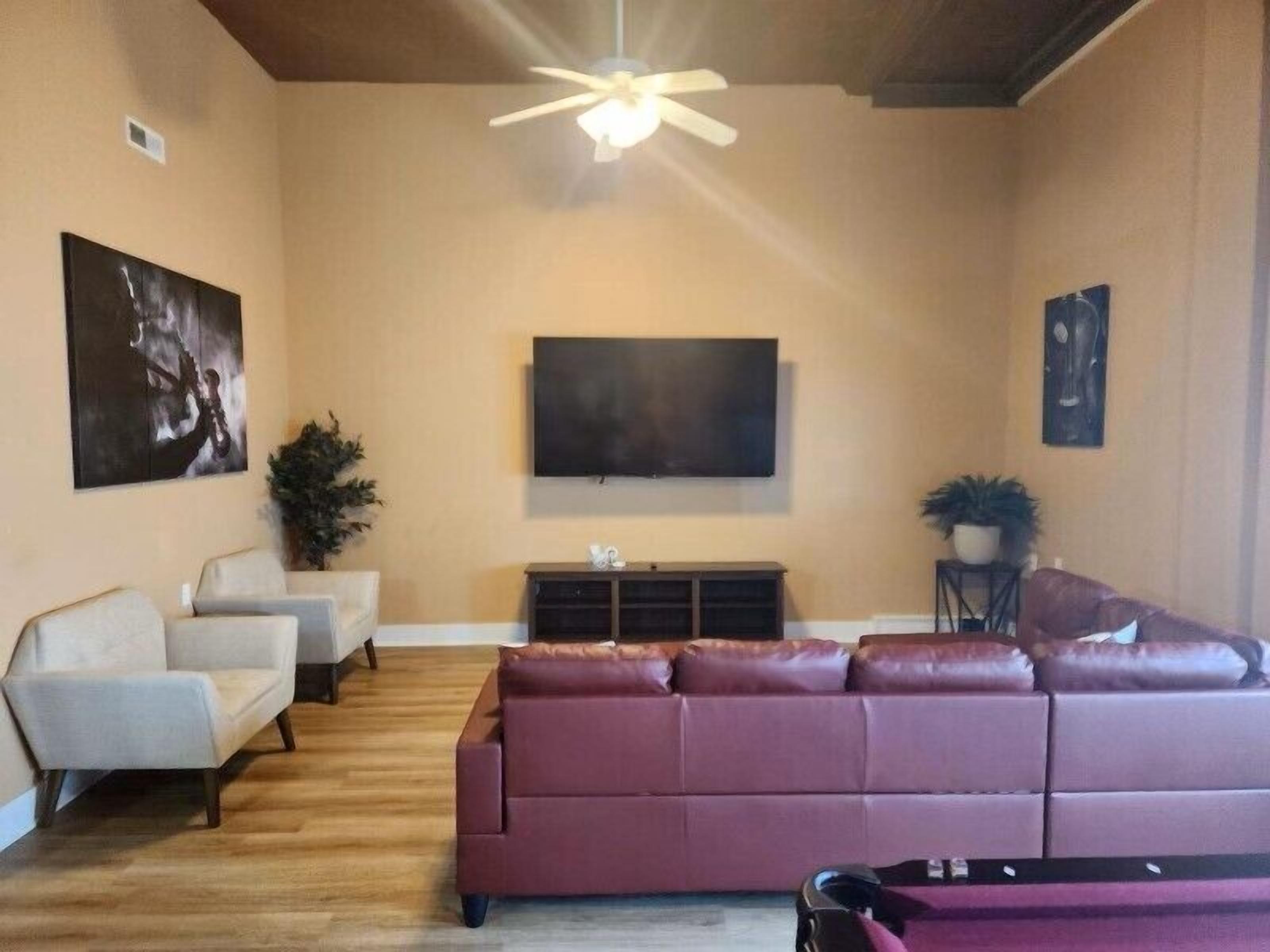 A living room with a large sectional sofa, a flat-screen TV, and a ceiling fan.