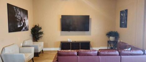 A living room with a large sectional sofa, a flat-screen TV, and a ceiling fan.