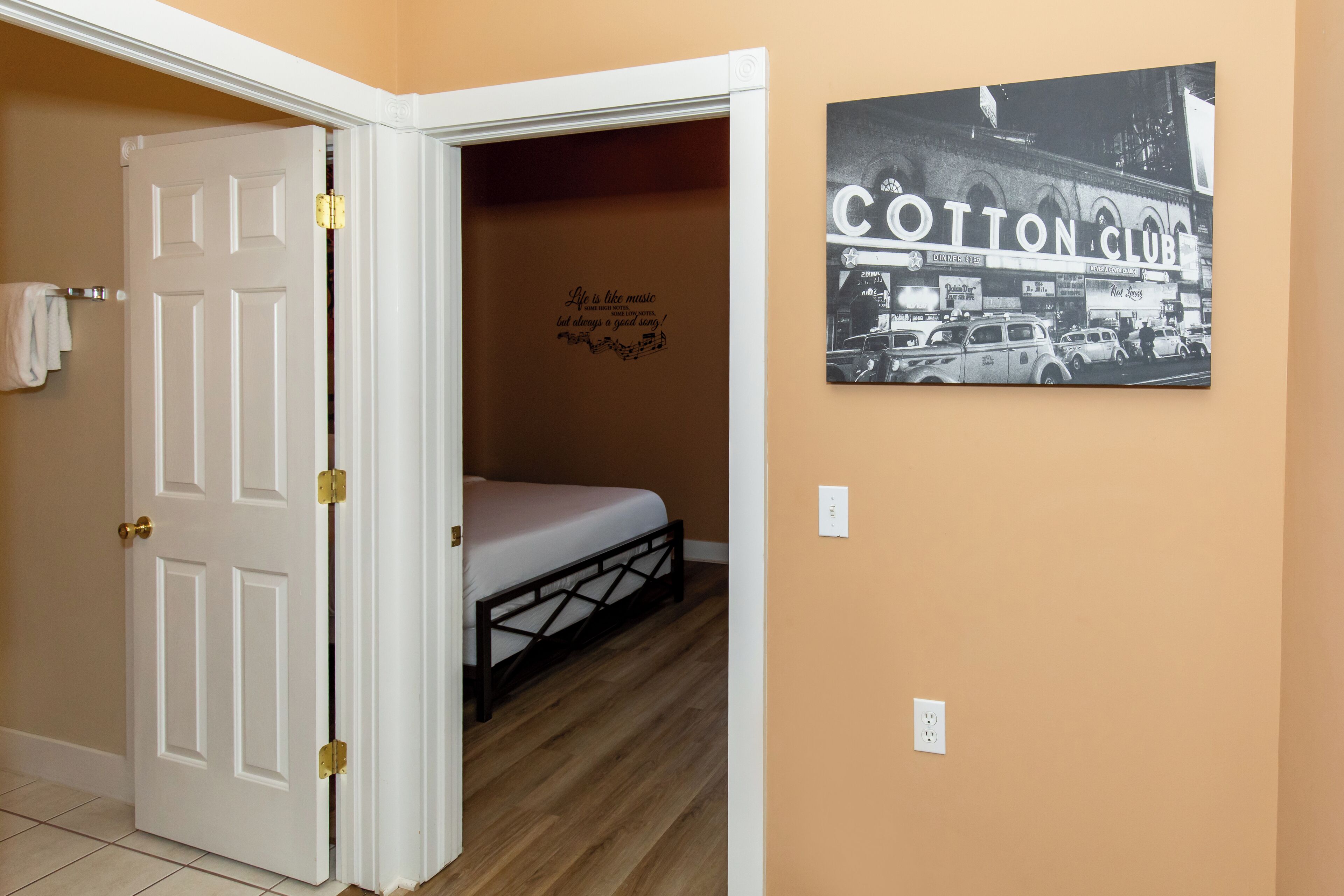A bedroom with a bed, a door, and a wall with a 'Cotton Club' sign.