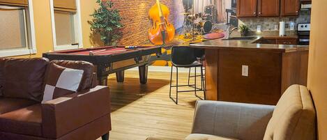 A cozy living area with a pool table, sofas, and a pool cue.