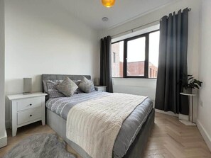 Relax in this serene bedroom with a large bed, bedside table, and potted plant.