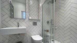 A modern bathroom with a white herringbone tile pattern, a glass shower enclosure, a white sink, and a toilet. - 1 Bed w/ Parking| Ideal for work stays By Tempstay (Slough)