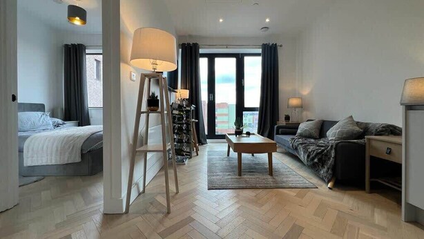 A modern hotel room with a bed, a sofa, a coffee table, and a view of the city. - 1 Bed w/ Parking| Ideal for work stays By Tempstay (Slough)