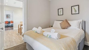 Hotellihuone, jossa on sänky, ovi toiseen huoneeseen ja pieni pöytä tuolilla.