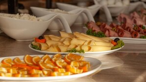 A buffet with various food items including sliced oranges, cheese, and ham. - BakurianiPearl (Borjomi)