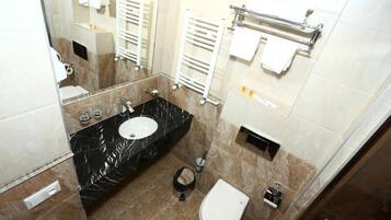 Un baño moderno con lavamanos de mármol, inodoro, bidé y un perchero para toallas.