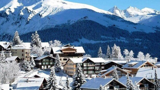 A snow-covered mountain resort with chalet-style buildings, a ski slope, and a forested backdrop. - BakurianiPearl (Borjomi)