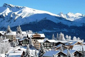 A snow-covered mountain resort with chalet-style buildings, a ski slope, and a forested backdrop. - BakurianiPearl (Borjomi)