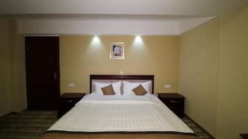 A hotel room with a large bed, two bedside tables, a door, and a framed picture on the wall.