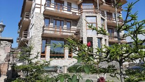 A multi-story building with balconies, stone facade, and a clear sky. - BakurianiPearl (Borjomi)