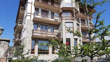 A multi-story building with balconies, stone facade, and a clear sky.