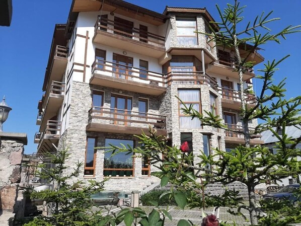 A multi-story building with balconies, stone facade, and a clear sky. - BakurianiPearl (Borjomi)