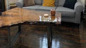 A living room with a grey sofa, a wooden coffee table, a mirror, and potted plants on a windowsill. - Boutique Downtown Suite | Walk to Shops & Cafés | Sleeps 6 (Armstrong)