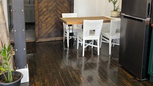A modern kitchen with a herringbone-patterned wooden wall, a black refrigerator, white chairs, and a wooden dining table. - Boutique Downtown Suite | Walk to Shops & Cafés | Sleeps 6 (Armstrong)