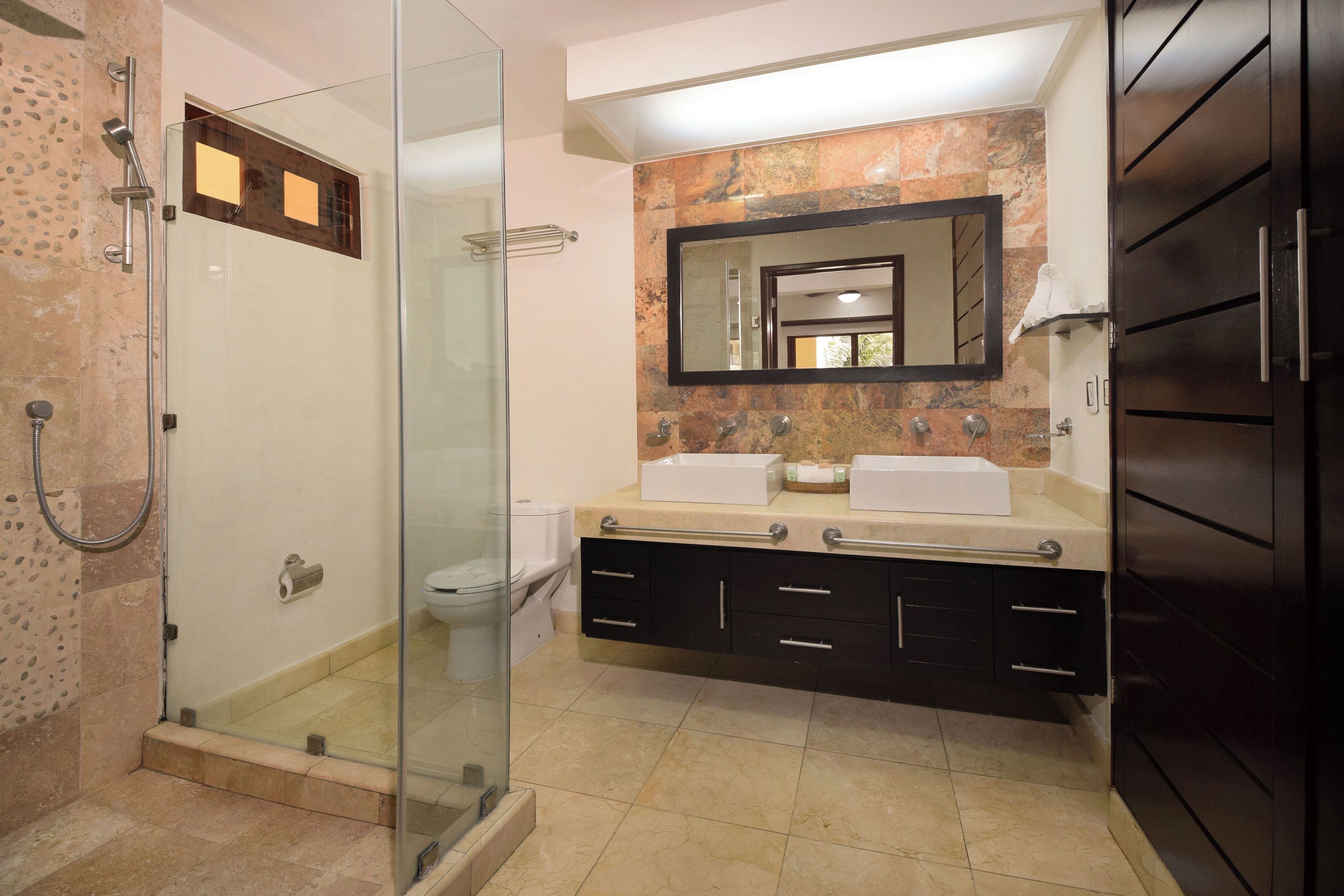 A modern bathroom with a glass-enclosed shower, a double sink vanity, and a large mirror.