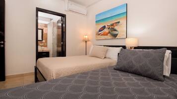Une chambre d’hôtel avec un lit, un tableau représentant une scène de plage, une table de chevet et une lampe.