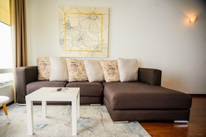 A modern living room with a sectional sofa, a white coffee table, and a patterned rug.