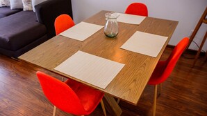 Een houten eettafel met vier stoelen, een glazen karaf en placemats.