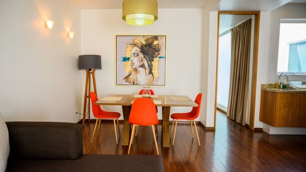 Een moderne eetruimte met een tafel, stoelen en een schilderij aan de muur.