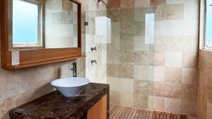 Een badkamer met een grote spiegel, een wit wastafelmeubel en een douche met glazen wanden.