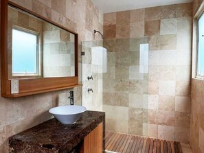 Un bagno con un grande specchio, un lavandino bianco e una cabina doccia in vetro.