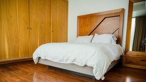 Een slaapkamer met een bed, een houten garderobe en een spiegel.