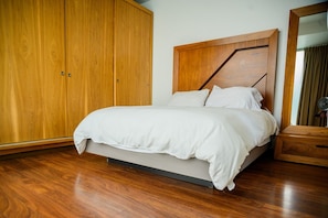 Una camera da letto con un letto, un'armadio in legno e uno specchio.