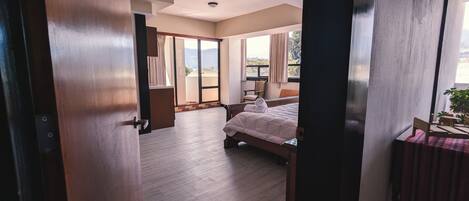 Quarto de hotel com cama, poltrona, mesa e vista para o exterior.