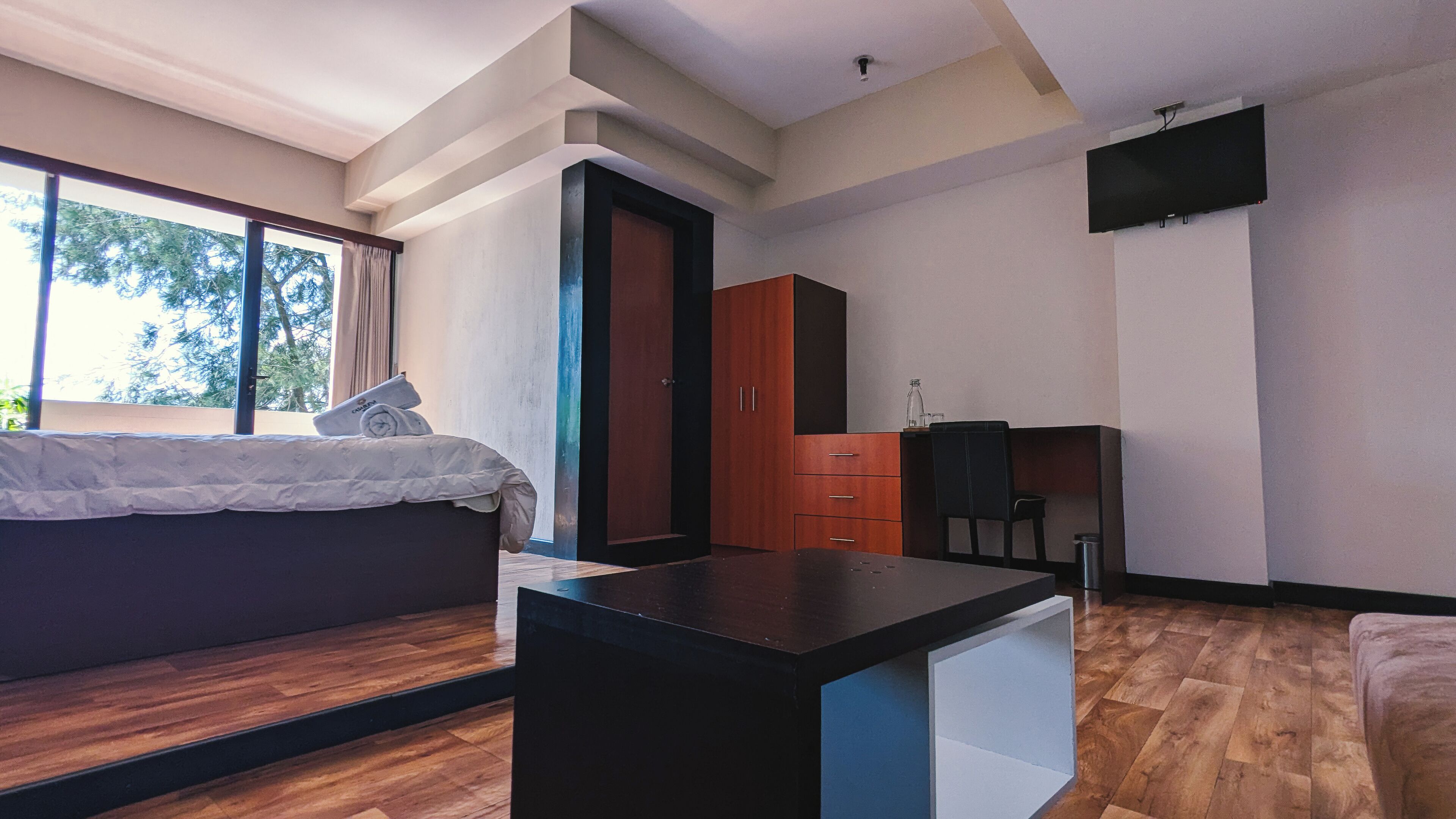 Una habitación moderna con cama, escritorio, televisor y armario.