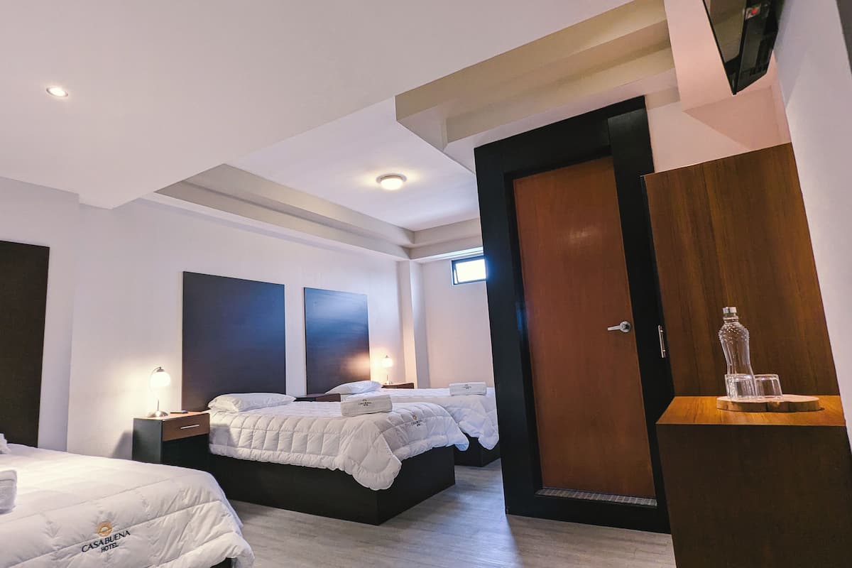 A modern hotel room with two beds, a wooden wardrobe, and a small table with a glass.